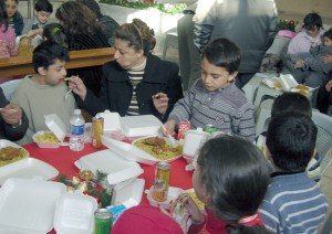 Children enjoy a hot meal at one of the dinners. One handicapped chiild needed assistance eating.