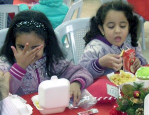 Two refugee girls enjoy their Christmas meal