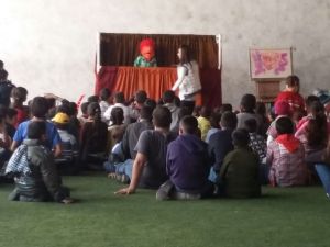 Children watch a puppet show explaining the birth of Christ before their meal