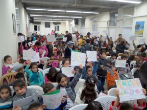 Part of the program included a coloring contest. Here children hold up their drawings hoping to win a small prize. Every child eventually received a gift.
