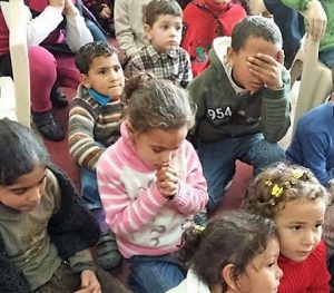 Christian refugee children bow their heads in prayer during one of our Christmas for Refugee programs.
