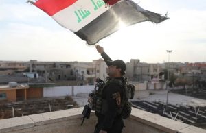 An Iraqi special forces soldiers waves an Iraqi flag from top of a church damaged by ISIS fighters in Bartella, east of Mosul, Iraq, October 21. 2016. REUTERS/Goran Tomasevic
