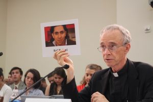 USCIRF Chair Thomas J. Reese, S.J. holds up a picture of Raif Badawi at a July 2016 Tom Lantos Human Rights Commission hearing on blasphemy laws