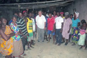 William J. Murray with survivors of the Agatu church massacre. Note that the roof is missing. The inside of the church was set on fire so there are no pews or chairs.